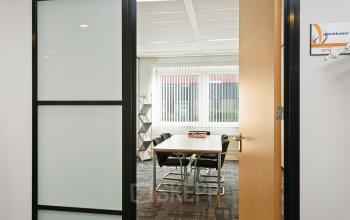 Interior office space rental at Linie 580-596, Apeldoorn, featuring a meeting table with black chairs and large windows for natural light.