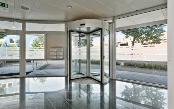 Bright and clean entrance with revolving door and large glass windows at an office building located at Linie 580-596 in Apeldoorn.