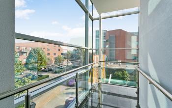 View from the interior glass balcony of office space rental at Linie 580-596, Apeldoorn, showing a modern exterior urban environment.