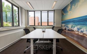 Modern office space rental at Het Rietveld 55A, Apeldoorn, with a large window, white walls, a conference table, and vibrant ocean-themed artwork.