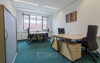 Office space rental at Het Rietveld 55A, Apeldoorn, featuring a clean, bright workspace with desks, chairs, and artworks on the wall.