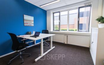 Modern office space rental at Het Rietveld 55A in Apeldoorn with a vibrant blue accent wall, neatly arranged desks, and bright natural light.