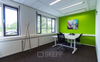 Modern office space rental at Het Rietveld 55A in Apeldoorn with a vibrant green accent wall, trendy art, and sleek furniture.