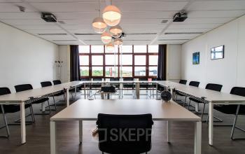 Bright office space rental at Het Rietveld 55A, Apeldoorn, with a large table, chairs, and modern lighting fixtures.