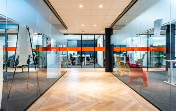 Modern office space with glass walls and parquet flooring at Landdrostlaan 51, Apeldoorn, suitable for office space rental.