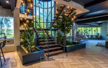 Spacious, furnished office interior with modern decor, wooden staircase, and large windows at Landdrostlaan 51, Apeldoorn, available for office space rental.