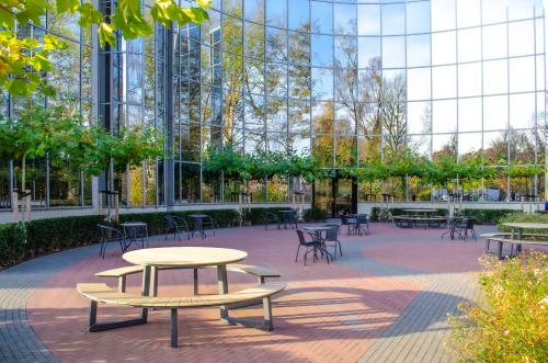 Exterior view of round office space with glass walls and outdoor seating at Landdrostlaan 51, Apeldoorn, ideal for office space rental.