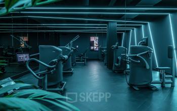 Modern gym with various exercise machines and blue LED lighting at Lange Amerikaweg 55-61, Apeldoorn, available for office space rental.