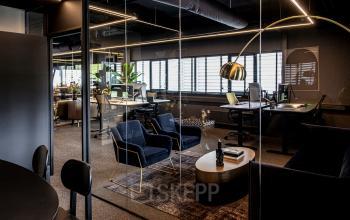 Modern office space in Apeldoorn with stylish furnishings, glass walls, and desks set up for work. Ideal for those looking to rent office space or interested in office space rental.