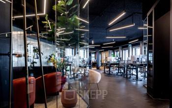 Modern office space with glass walls and stylish lighting; a mix of seating and workstations. Ideal for office space rental.