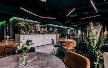 Stylish office space in Apeldoorn with modern furnishings, including round tables, chairs, and plants. Suitable for rent office space or office space rental.