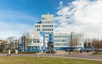 Exterior view of a multi-story office building at Prins Willem Alexanderlaan 701, Apeldoorn, featuring large windows. Ideal for office space rental purposes with convenient access and parking facilities.