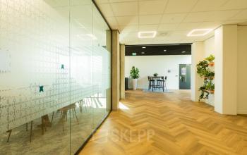 Bright office interior at Prins Willem Alexanderlaan 701, Apeldoorn, featuring wooden flooring and modern glass-walled conference room, ideal for workspace rental.