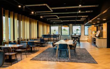 Spacious, modern office to rent at Prins Willem Alexanderlaan 701, Apeldoorn, featuring stylish furnishings, wood accents, and abundant natural light ideal for collaborative activities.