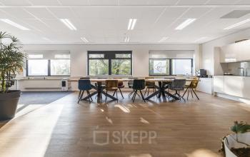 Spacious office interior at Waterloseweg 7a in Apeldoorn, featuring modern furnishings, large windows, and a sleek wooden floor, ideal for open floor plan office space rental. Bright and inviting ambiance.