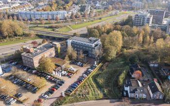 Aerial view of the office building at Waterloseweg 7a, Apeldoorn, featuring parking lots and surrounding greenery, ideal for office space rental.