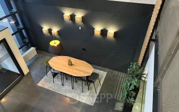 Modern office workspaces at Waterloseweg 7a, Apeldoorn, featuring a sleek table, contemporary lighting, and greenery. Ideal for those seeking an office space rental with a professional yet stylish atmosphere.