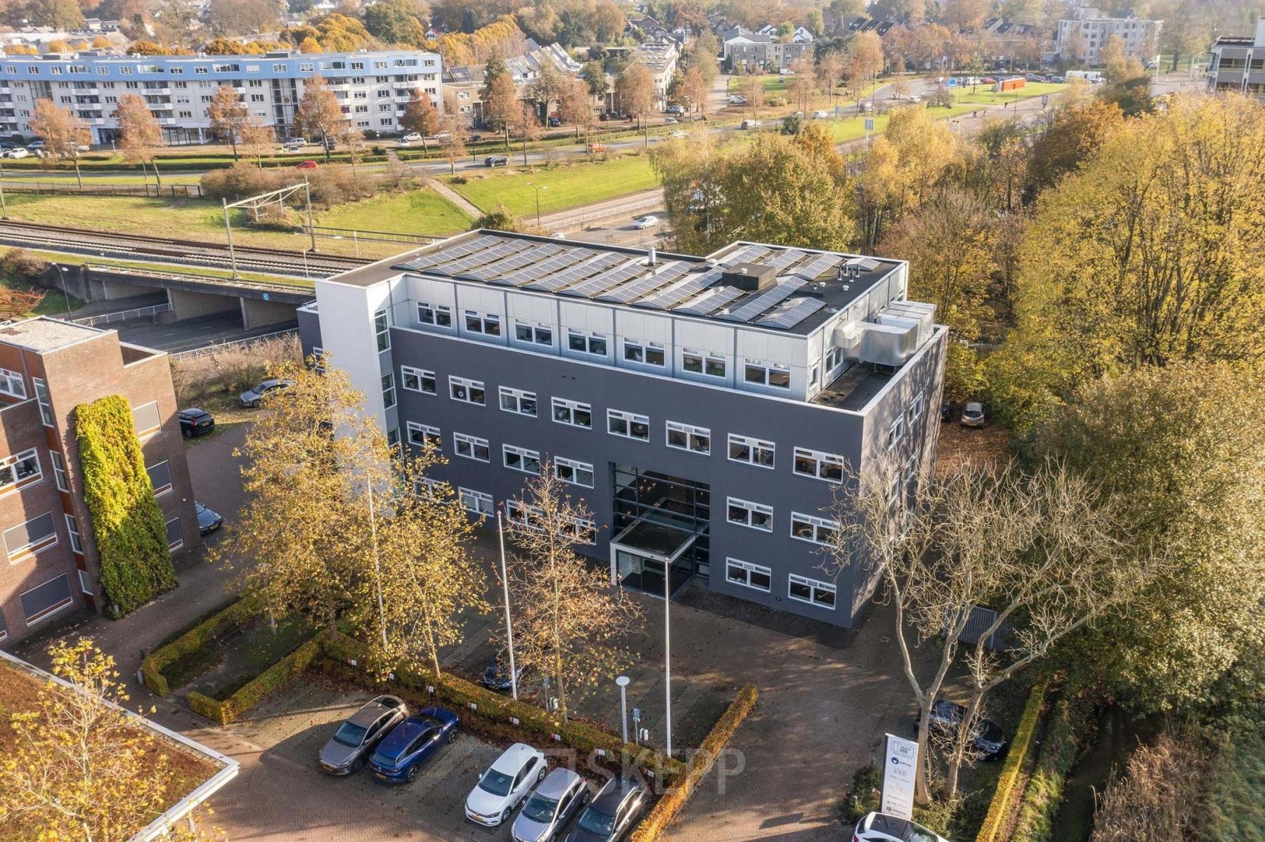 A modern office building located at Waterloseweg 7a in Apeldoorn, featuring multiple stories and large windows, surrounded by trees and a parking area. Ideal for office space rental opportunities.