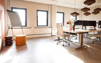 Furnished office space rental at Schumanpark 9, Apeldoorn featuring modern desks, chairs, and vibrant decor.
