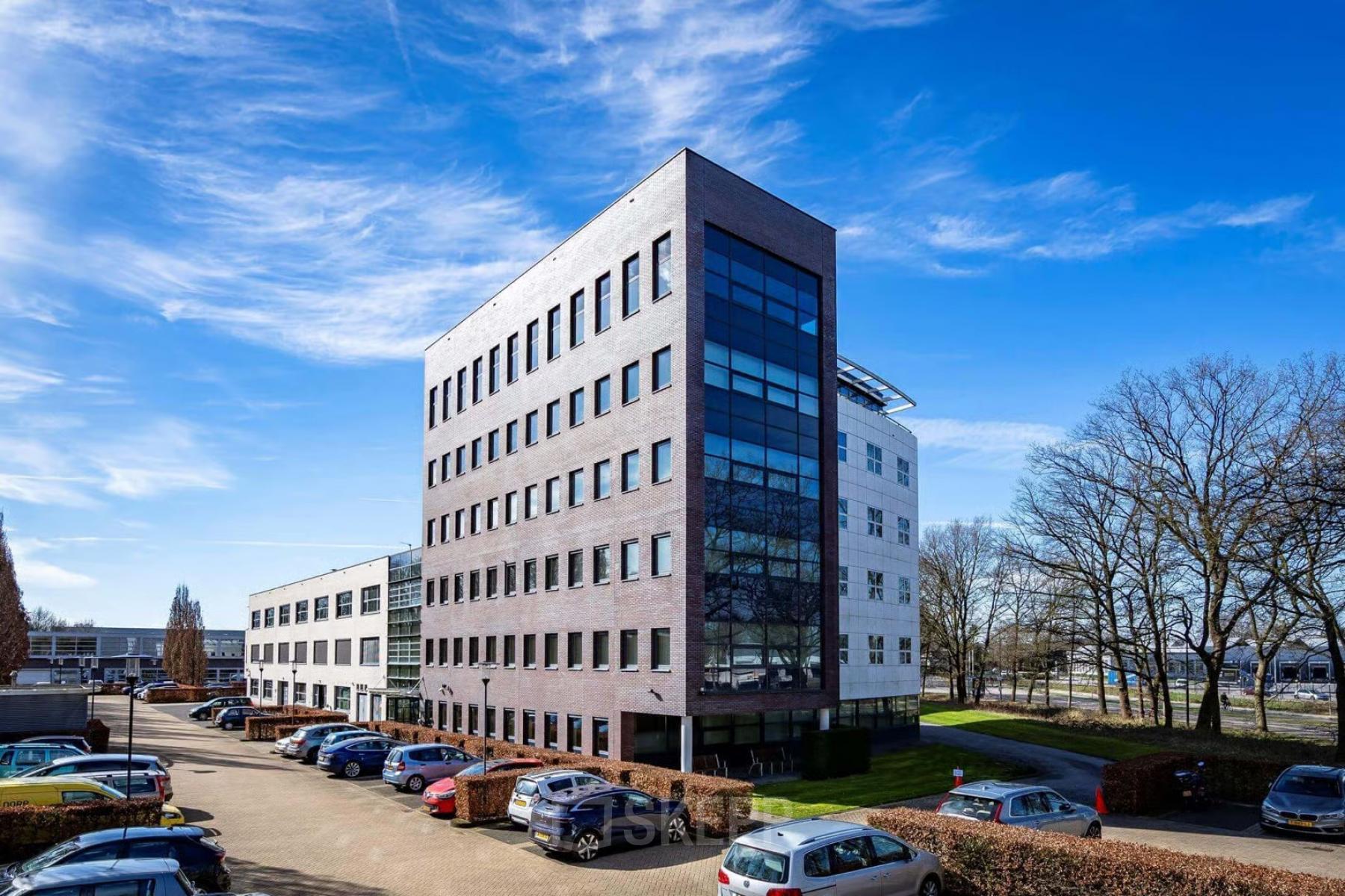 Exterior view of an office building at Schumanpark 9, Apeldoorn, suitable for office space rental, with ample parking space visible.