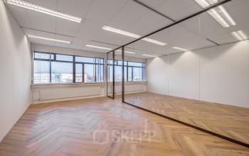 Spacious office for rent at Oude Apeldoornseweg 41-45, Apeldoorn featuring large windows and a wooden floor.