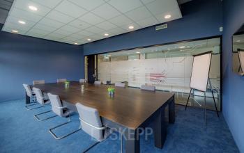 Modern conference room with a large table and chairs, featuring a blue color scheme at Oude Apeldoornseweg 41-45, ideal for office space rental.