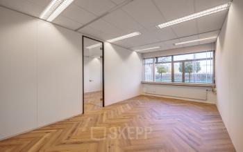 Bright office space with wooden flooring located at Oude Apeldoornseweg 41, Apeldoorn, featuring large window and modern lighting, ideal for office space rental.