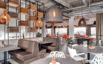 Modern office space with wooden crate decor, plush seating booths, stylish hanging lights, and a mix of seating options at Oude Apeldoornseweg 41, Apeldoorn. Ideal for office space rental.