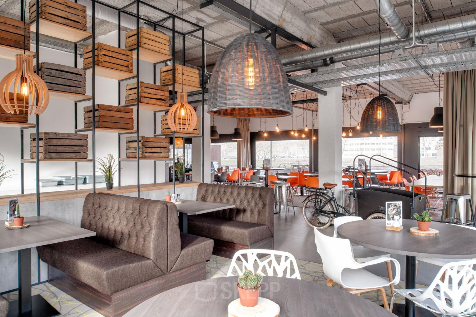 Modern office space with wooden crate decor, plush seating booths, stylish hanging lights, and a mix of seating options at Oude Apeldoornseweg 41, Apeldoorn. Ideal for office space rental.