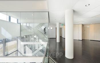 Modern office space with white walls and glass partitions at Laan van Malkenschoten 40, Apeldoorn, ideal for office space rental.