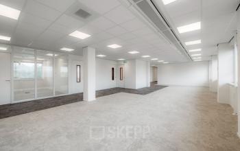 Empty office space for rent with white walls and glass partitions at Laan van Malkenschoten 40 in Apeldoorn.
