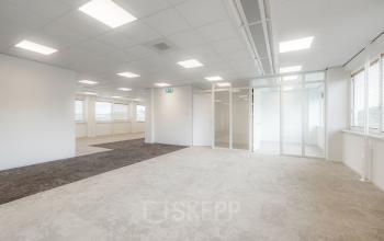 Modern office space at Laan van Malkenschoten 40 in Apeldoorn featuring carpeted flooring, glass partitions, and ample natural light for a professional business environment.