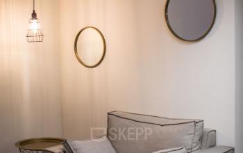 Cozy furnished office lounge area with soft armchairs and a side table, located at Roggestraat 111, Apeldoorn.