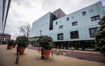 Modern office building located at Roggestraat 111, Apeldoorn with a contemporary facade, large windows, and potted plants lining the walkway, perfect for office space rental.