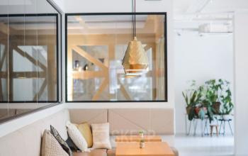 Modern office interior at Roggestraat 111, Apeldoorn, featuring cozy seating areas and wooden tables under stylish lighting, perfect for office space rental.