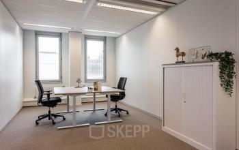 Bright office to rent at Roggestraat 111, Apeldoorn, featuring modern desks, chairs, and a storage cabinet by the window.
