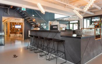 Modern office space for rent in Apeldoorn at Roggestraat 111 featuring a sleek bar area with stools and contemporary lighting.