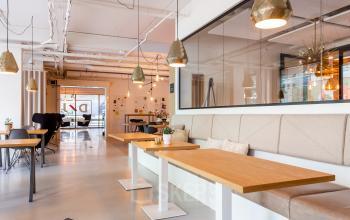 Modern office space rental at Roggestraat 111 in Apeldoorn, featuring open tables and pendant lighting.