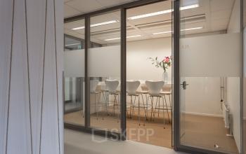 Interior view of Roggestraat 111 office space rental in Apeldoorn, featuring a modern conference room with high chairs and a table.