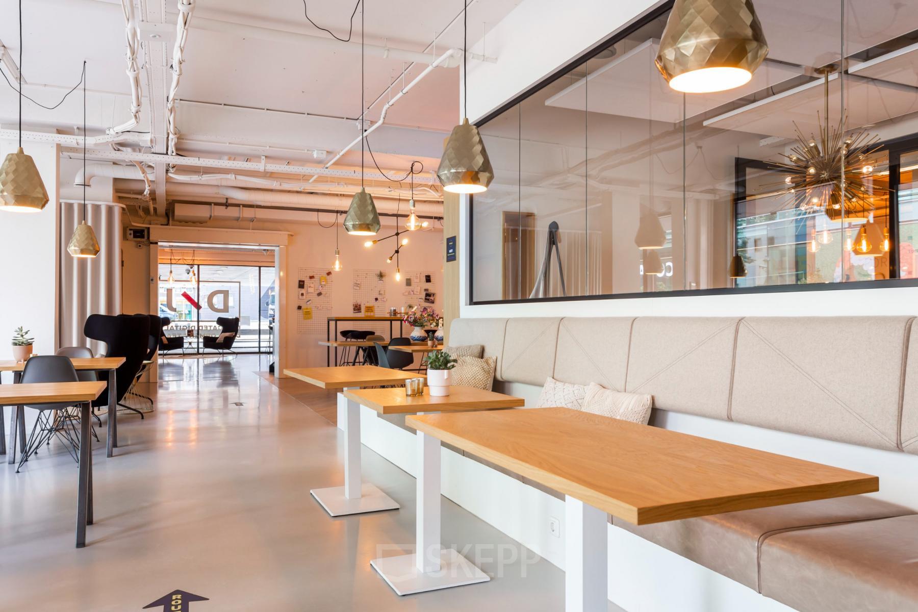 Modern office space rental at Roggestraat 111 in Apeldoorn, featuring open tables and pendant lighting.