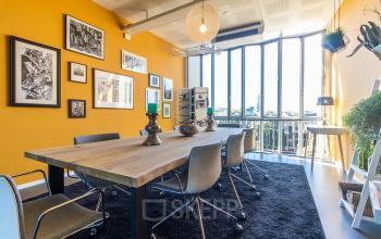 Bright office to rent at Jansbuitensingel 7, Arnhem Centrum, featuring a furnished meeting area with large windows and vibrant decor.