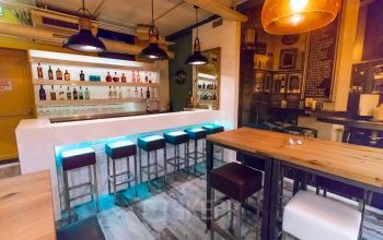 A modern office lounge in Arnhem Centrum at Jansbuitensingel 7, featuring a stylish bar setup with high stools and ambient lighting, ideal for rent office space activities.