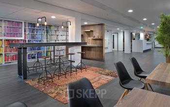 Modern office space at Vossenstraat 6, Arnhem Centrum with colorful bookshelves, high tables, and chairs for collaborative work.