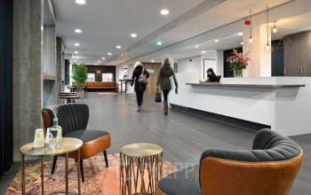 Modern office space in Arnhem Centrum at Vossenstraat 6 featuring a reception area with contemporary seating and people walking through the space.