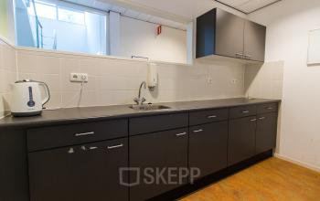 A tidy pantry area with dark cabinetry and a kettle in office space rental at Meander 251, Arnhem IJsseloord.