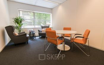 Tastefully furnished lounge area with comfortable seating and a round table, ideal for an office space rental at Meander 251, Arnhem IJsseloord.