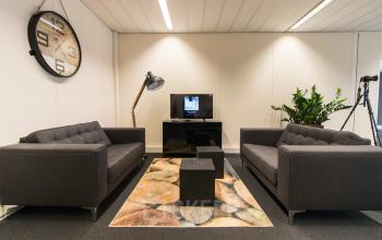 Modern lounge area with comfortable sofas and a television at office space rental in Arnhem IJsseloord, Meander 251.