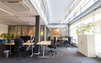 Modern office space rental at Meander 251, Arnhem IJsseloord, with workers engaged at their desks and a vibrant office atmosphere.