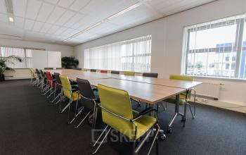 Spacious office space rental at Meander 251, Arnhem IJsseloord, with a large conference table, green chairs, and bright natural light.