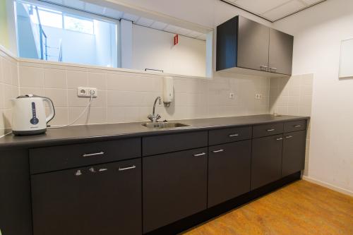 A tidy pantry area with dark cabinetry and a kettle in office space rental at Meander 251, Arnhem IJsseloord.